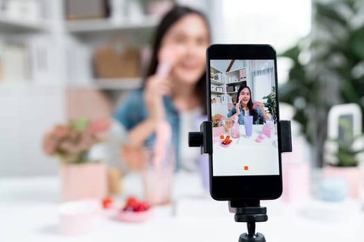 Selective focus smartphone with young beautiful Asian reviewing cosmetic makeup brush cheek test collection with pastel color, showing glow blusher mood to promote on social media online. Stratagem.