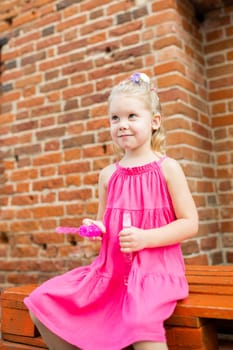 Child girl walks and have fun outdoor with cochlear implant on the head. Hearing aid and treatment concept. Copy space vertical.