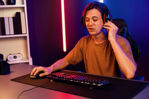 Host channel of gaming smart streamer playing online game to be winner, wearing headphone with viewers live steaming on media social online for selected team competition at neon light room. Pecuniary.