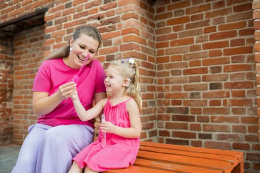 Deaf child with cochlear implant for hearing audio and aid for impairment having fun and laughs with mother outdoor in summer. Sound fitting device to help with communication listening and interaction.