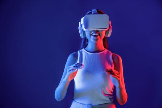 Smart Female standing surrounded by neon light wear VR headset connecting metaverse, futuristic cyberspace community technology, using both hands interact with generated virtual object. Hallucination.