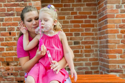 Deaf child with cochlear implant for hearing audio and aid for impairment having fun and laughs with mother outdoor in summer. Sound fitting device to help with communication listening and interaction.