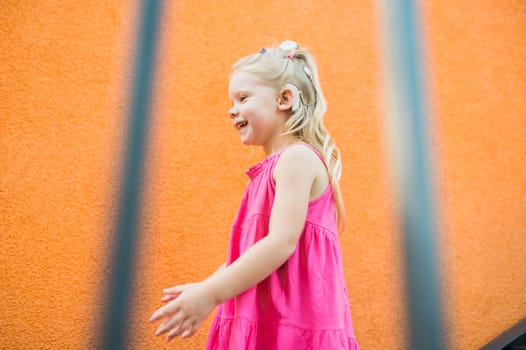 Child with hearing problem and cochlear implant dance in street, deaf kid began to hear. Hearing loss in childhood and treatment concept. Copy space and empty place for text.