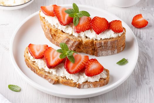 Homemade Crispbread toast with Cottage Cheese and Strawberry on white wooden board.