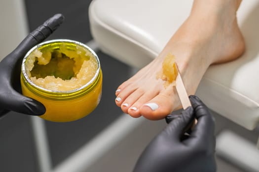 Peeling feet pedicure procedure in a beauty salon. Sugar scrub and relax beauty procedure.