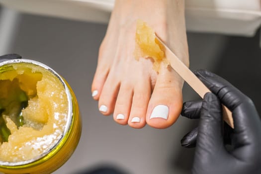 Peeling feet pedicure procedure in a beauty salon. Sugar scrub and relax beauty procedure.