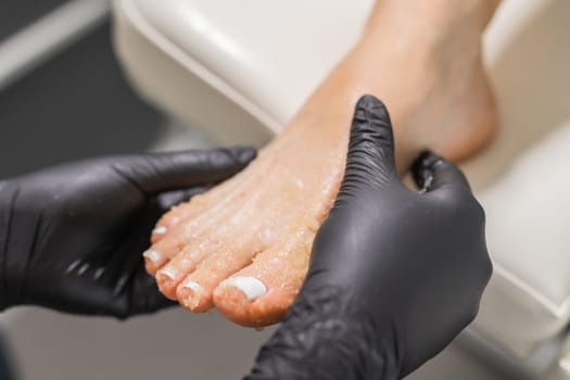 Peeling feet pedicure procedure in a beauty salon. Sugar scrub and relax beauty procedure.