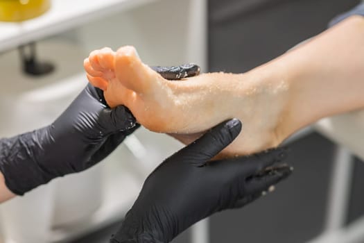 Peeling feet pedicure procedure in a beauty salon. Sugar scrub and relax beauty procedure.