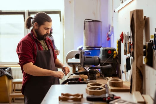 Cabinetmaker in joinery putting on protection glasses before assembling furniture. Woodworking professional preparing safety gear in carpentry studio before starting work