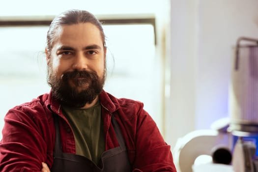 Portrait of smiling carpenter in woodworking shop proud of his work in furniture assembling business. Focus on upbeat cabinetmaker in joinery having crafting occupation, close up shot