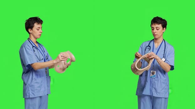 Specialist presenting cervical neck collar used for physical therapy and trauma after an accident or fracture, greenscreen backdrop. Nurse shows orthopedics brace to help with spine injury. Camera B.