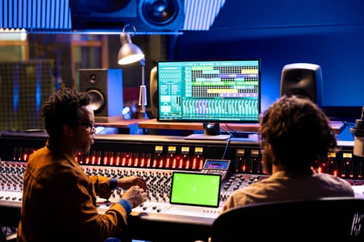 Musician and sound producer look at isolated mockup on tablet, using mixing and mastering techniques to create songs. Musicians team editing music with digital audio software app.