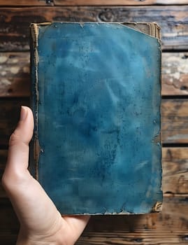 The person is holding an Azure blue book in their hand, with a rectangular shape. Their finger points to the electric blue cover, showing a gesture of appreciation for art