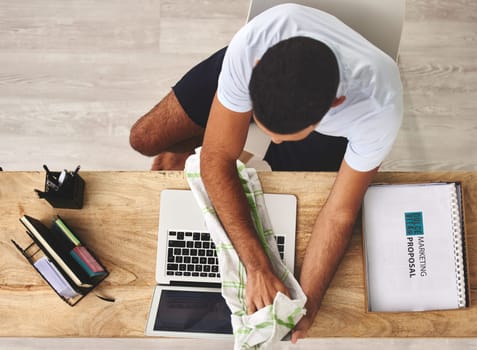 Remote work, home and man with cleaning of laptop on desk for hygiene, maintenance and dust. Cloth, wipe and creative person with technology for marketing proposal, research and safety from above.