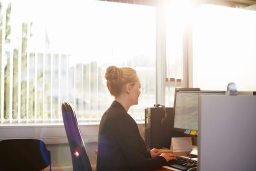 Business woman, computer and working at office desk with email, planning and software for human resources. Worker, employee or person typing on desktop PC for information and organizing in lens flare.