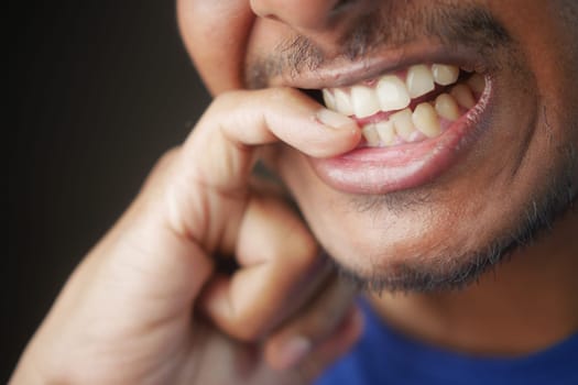 young men biting his nails at home