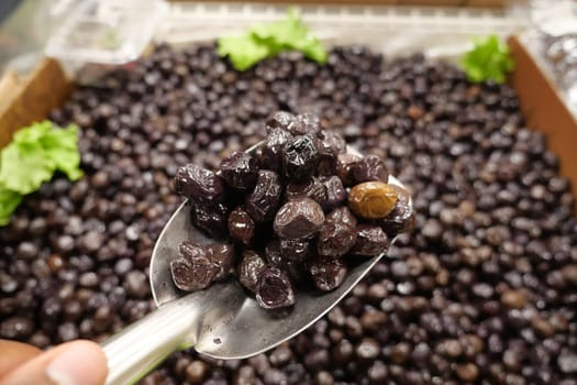 slices black olives with spoon in a bowl