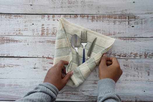 person hand cleaning and drying cutlery with a towel,