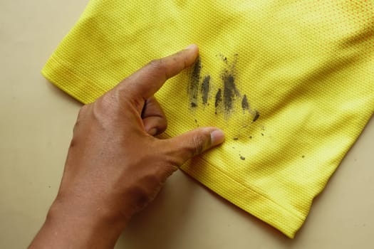 man holding dirty shirt, showing making stain,