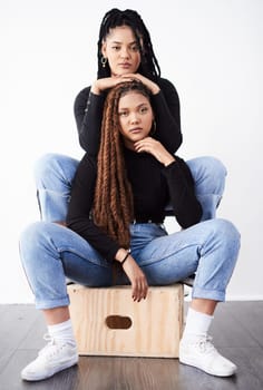 Lesbian couple, portrait and fashion in studio with confidence for style inspiration, white sneakers and love. Serious, lgbt and black people together for support, relationship and braids with jeans.
