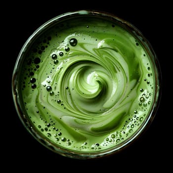 A refreshing drink made from water, liquid vegetables, and fruits. The smoothie is green in color with a beautiful swirl in the middle, resembling a liquid circle of dew