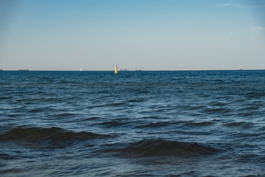 Yellow Lighthouse on blue sea line. Waves on sunny day on Baltic sea. Gdansk Poland. Coastline