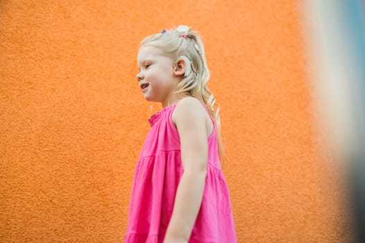 Child girl walks and have fun outdoor with cochlear implant on the head. Hearing aid and treatment concept. Copy space vertical.