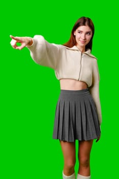 A smiling young woman wearing a casual white hoodie stands against a vibrant green screen background. She is gesturing upwards with her index finger, as if pointing out something important or having a bright idea.