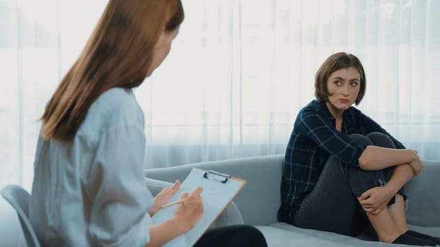 Sad PTSD woman patient in therapy for mental health with psychologist, depression or grief after life failure. Frustrated trauma young woman talking to prim psychologist about emotion in clinic