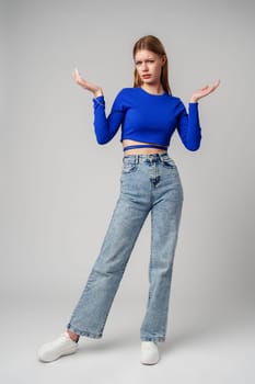 Young Woman in Blue Top Holding Out Hands in studio