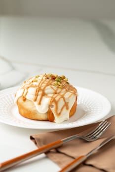 Cinnamon roll bun with icing on plate close up