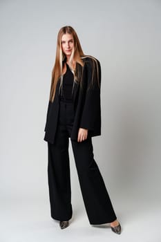 Young Woman Model in Black Top and Pants Posing on gray background in studio