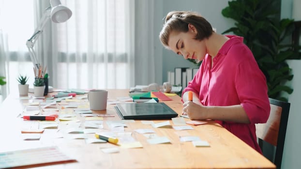 Top view of designer writing idea on colorful sticky notes while sitting at meeting table with tablet display logo design. Professional business woman looking design and making a decision. Symposium.