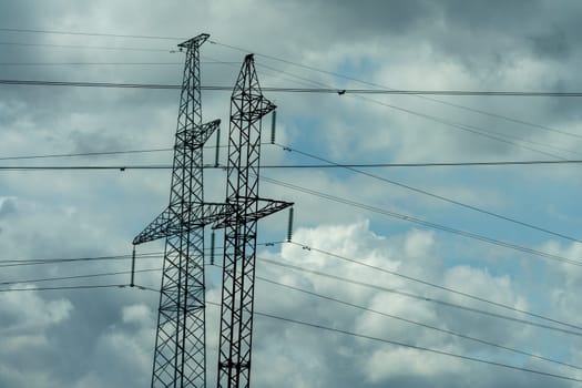 High voltage towers with sky background. Power line support with wires for electricity transmission. High voltage grid tower with wire cable at distribution station. Energy industry, energy saving.