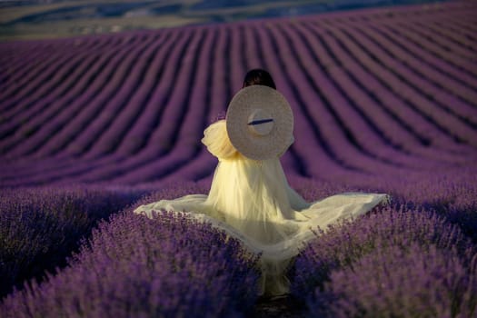 Woman lavender field sunset. Back view woman in yellow dress and hat. Aromatherapy concept, lavender oil, photo session in lavender.