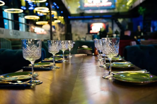 A table with a number of wine glasses and plates. The table is set for a meal. Scene is elegant and sophisticated