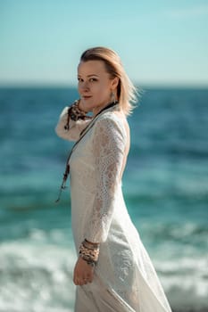 Woman beach sea white dress. The middle-aged looks good with blonde hair, boho style in a white long dress with beach decorations on the neck and arms