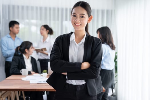 Portrait of happy young asian businesswoman looking at camera with motion blur background of business people movement in dynamic business meeting. Habiliment