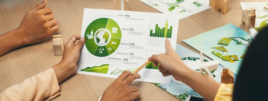 Professional businessman interested in invested in green businesses when he see rising graph on table with environmental document and wooden block scatter around. Closeup. Focus on hand. Delineation.