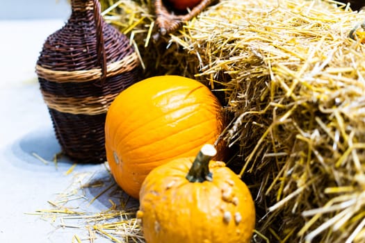 Orange halloween pumpkins on stack of hay or straw in a sunny day, fall display