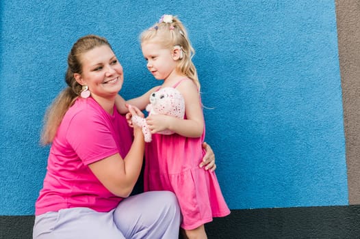 Deaf child with cochlear implant for hearing audio and aid for impairment having fun and laughs with mother outdoor in summer. Sound fitting device to help with communication listening and interaction.