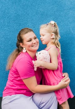 Deaf child with cochlear implant for hearing audio and aid for impairment having fun and laughs with mother outdoor in summer. Sound fitting device to help with communication listening and interaction.