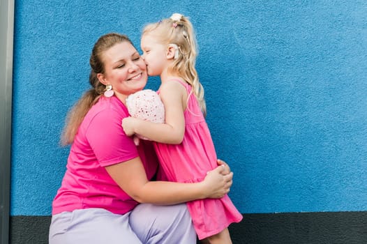 Blonde little girl with cochlear implant playing with her mother outdoor. Hear impairment deaf and health concept. Diversity and inclusion. Copy space.