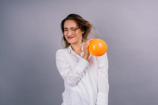 Portrait of beautiful woman with ballon in hands on grey background in studio