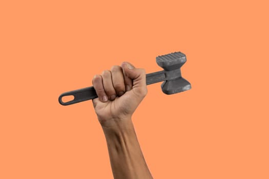 Black male hand holding a kitchen hammer isolated on orange background background. High quality photo