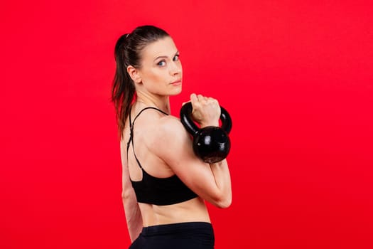 Sport, active lifestyle concept. Smiling strong and slim fitness female athlete holding kettlebells