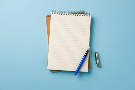 Top view of notebook and fountain pen on blue background