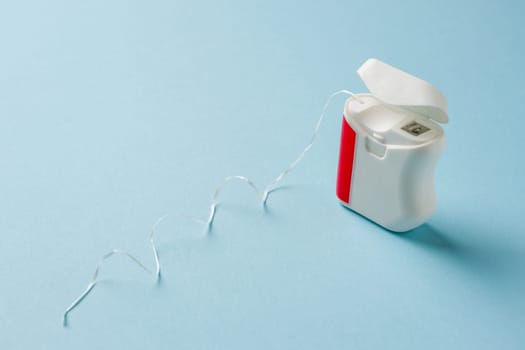 Top view of dental floss in white box on blue background