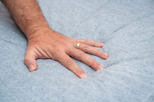 The man checks the quality and softness of the new mattress he will buy by pressing it with his hand