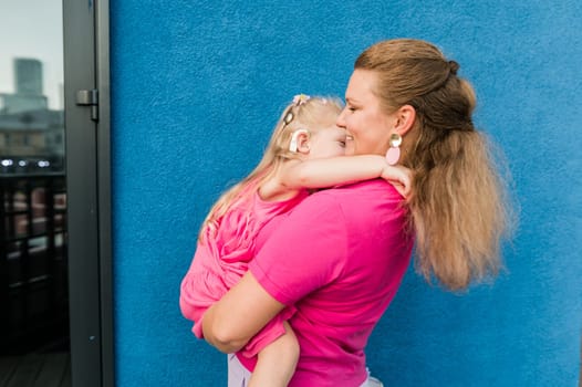 Deaf child with cochlear implant for hearing audio and aid for impairment having fun and laughs with mother outdoor in summer. Sound fitting device to help with communication listening and interaction.